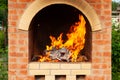 Brick stove in the yard with large flames from the fire in preparation for cooking meat in the open air Royalty Free Stock Photo