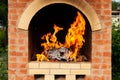 Brick stove in the yard with large flames from the fire in preparation for cooking meat in the open air Royalty Free Stock Photo