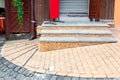 Brick threshold on the slope with granite steps to the open wooden entrance door.