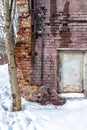 Brick wall of an abandoned warehouse with smudges from melting snow, with a rusty metal door Royalty Free Stock Photo