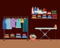 Brick wall background of clothes in hangers with table and clothes iron and elements of home laundry