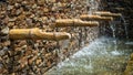 Brick wall with a bamboo stick spillway waterfall splashing down into a pool Royalty Free Stock Photo