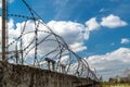 Brick wall with barbed-wire against the blue sky. Royalty Free Stock Photo
