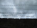 Brick Wall With Barbed Wire, Against a Dark Cloudy Sky Royalty Free Stock Photo