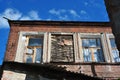 Brick wall of building with one boarded up broken window, view from top on slate roof and blue sky Royalty Free Stock Photo