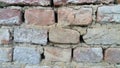 Brick wall. Ceramic brickwork or fence. Old, uneven brick, covered in some places with moss. Texture of crumbling stone with moss Royalty Free Stock Photo