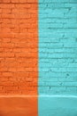 Brick wall, divided in half and painted with orange and turquoise paint