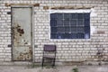 Brick wall with glass bricks window, rusted doors, old chair Royalty Free Stock Photo