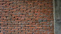 A brick wall with a gray cement base. The wall is made of red bricks and has a rough texture Royalty Free Stock Photo
