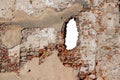 Brick wall with a hole. Texture of old broken rough brickwork with cracks and peeling plaster. Royalty Free Stock Photo