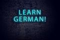 Brick wall and neon sign with inscription. Concept of learning german