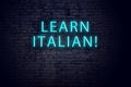 Brick wall and neon sign with inscription. Concept of learning italian