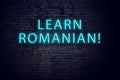 Brick wall and neon sign with inscription. Concept of learning romanian Royalty Free Stock Photo