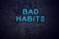 Brick wall and neon sign with text bad habits