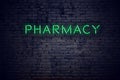 Brick wall at night with neon sign pharmacy