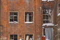 Brick wall of an old abandoned house with broken glasses in the windows and with snow drifts Royalty Free Stock Photo