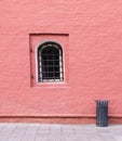 Brick wall painted red with lattice window and garbage bin. background, architecture Royalty Free Stock Photo