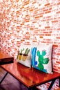 Brick wall with pillow on wooden table in cafe, background and copy space Royalty Free Stock Photo