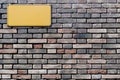 A brick wall with a rectangular yellow plaque attached Royalty Free Stock Photo