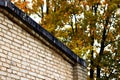 Brick wall and roof on the background of the autumn tree Royalty Free Stock Photo