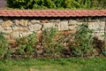 Brick wall of stone blocks of yellow color. the roof of the wall made of burnt tiles protects the crown from the soaking of rain a Royalty Free Stock Photo