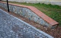 Brick wall of stone blocks of yellow color. the roof of the wall made of burnt tiles protects the crown from the soaking of rain a Royalty Free Stock Photo