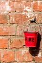 A brick wall on which hangs a red bucket called Royalty Free Stock Photo