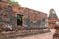 The brick wall with window of church and small stupa in the ruins of ancient remains at Wat Worachet temple. Royalty Free Stock Photo