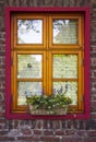 Brick wall with windows and flower boxes with flowering plants Royalty Free Stock Photo