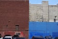 Brick walls painted in white, blue and brown behind a parking lot
