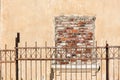 Bricked up window on a broken old house. metal fence in front. Royalty Free Stock Photo