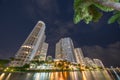 Brickell Key Miami highrise condominiums. Long exposure photo shot at night with blurry clouds and palm trees. Water smooth