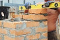 Bricklayer Bricklaying Concept. Bricklaying Tools. A bricklayer using a level to check his new house construction wall outdoor. Br