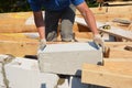 Bricklayer builder laying autoclaved aerated concrete blocks for house wall near unfinished roof eaves Royalty Free Stock Photo