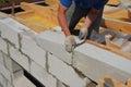 Bricklayer builder laying autoclaved aerated concrete blocks for house wall near unfinished roof top