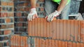 Bricklayer Building Wall with Red Bricks. Close-up of a construction worker laying red bricks with mortar, showcasing Royalty Free Stock Photo