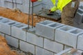 The bricklayer construction worker is laying down another row of cement blocks in the construction site