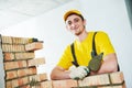 Bricklayer. Portrait of young smiling construction mason near brick wall Royalty Free Stock Photo