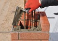 Bricklayer hand laying brick column with metal rod