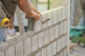 bricklayer hands hold aluminium brick trowel installing brick blocks on construction site Royalty Free Stock Photo