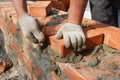 Bricklayer hands in masonry gloves bricklaying new house brick wall. Masonry close up
