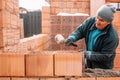 Bricklayer industrial worker installing brick masonry on exterior wall with trowel putty knife Royalty Free Stock Photo