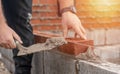 Bricklayer laying brick on cement mix on construction site close-up. Reduce the housing crisis by building more affordable houses Royalty Free Stock Photo