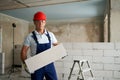 Bricklayer or mason constructs wall of autoclaved aerated concrete blocks. Portrait of brickwork worker contractor