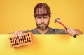 bricklayer. mature man in helmet with hammer and brick. builder bearded worker