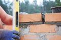 Bricklayer measure brick wall with spirit level. Bricklaying new house wall