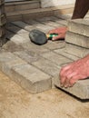 Bricklayer places concrete paving stone blocks for building up a patio hammer tool Royalty Free Stock Photo