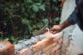 Bricklayer placing and adjusting bricks with mortar, putty knife and trowel. Professional construction worker building exterior