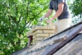 Bricklayer repair brick chimney on asbestos house rooftop