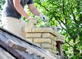 Bricklayer repair brick chimney on asbestos house rooftop close up